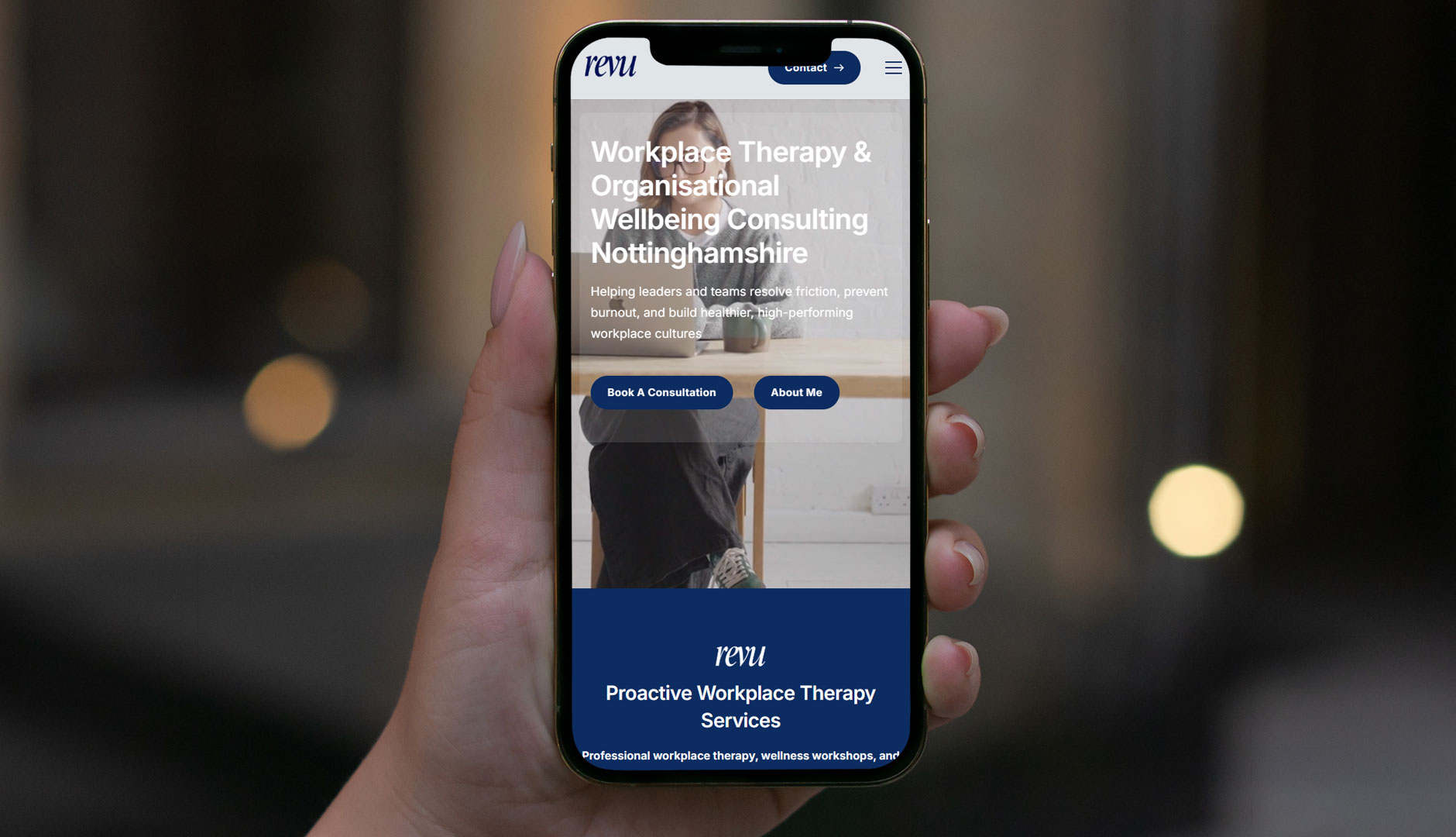 Hand holding a phone displaying a workplace therapy website.